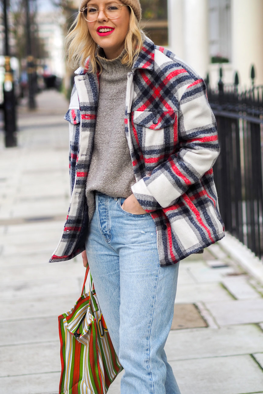 Alex Stedman of The Frugality wearing a red and white check over coat from Very along with a grey knitted roll-neck jumper from H&M, stone wash Gap jeans, Ace and Prince bag.