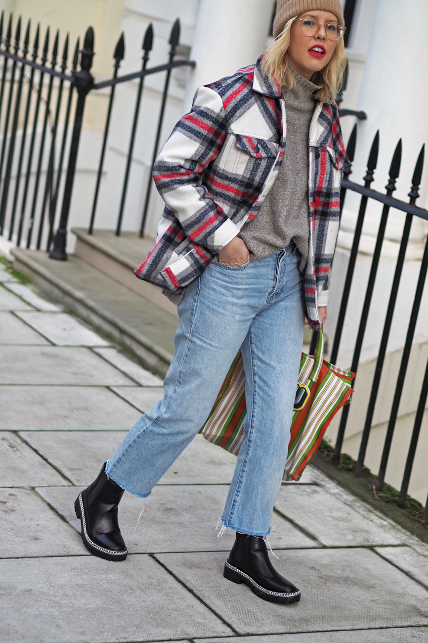 Alex Stedman of The Frugality wearing a red and white check over coat from Very along with a grey knitted roll-neck jumper from H&M, stone wash Gap jeans, Ace and Prince bag and black studded boots from Very.