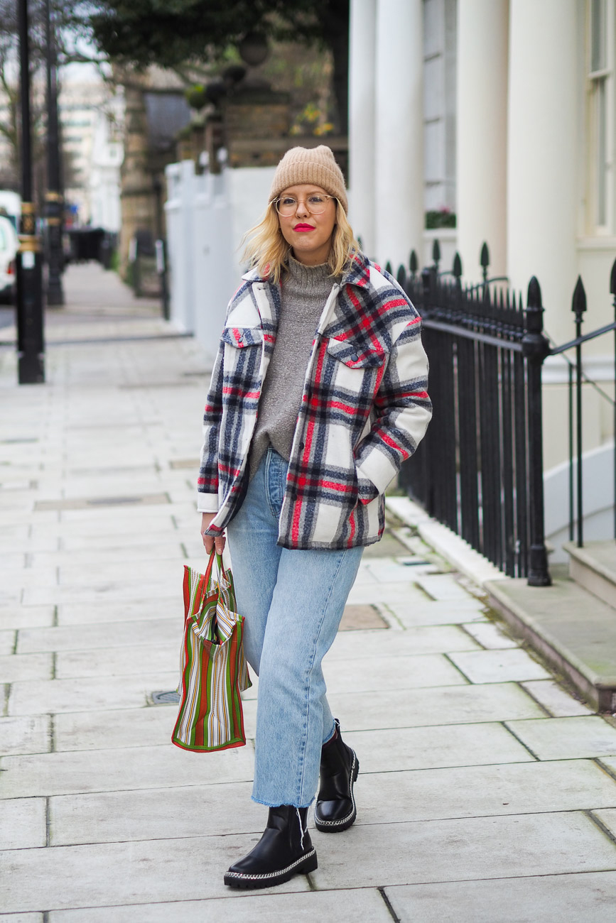 Alex Stedman of The Frugality wearing a red and white check over coat from Very along with a grey knitted roll-neck jumper from H&M, stone wash Gap jeans, Ace and Prince bag and black studded boots from Very.